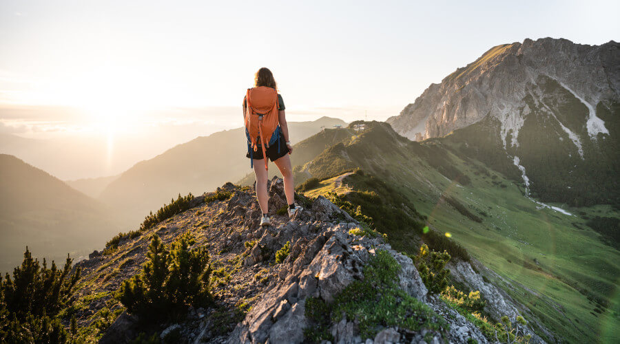 Frau auf einem Berggipfel im Sommer im Abendlicht