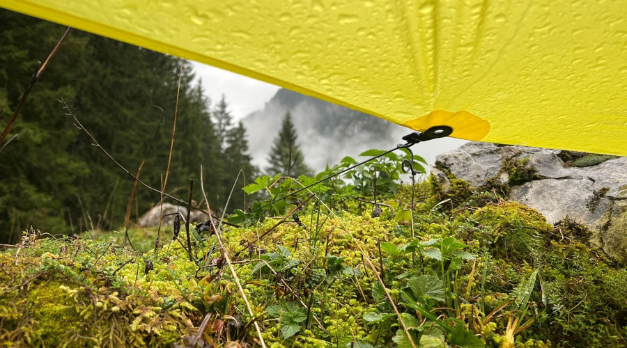 Bergwiese bei schlechtem Wetter unter einer gelben Zeltblache