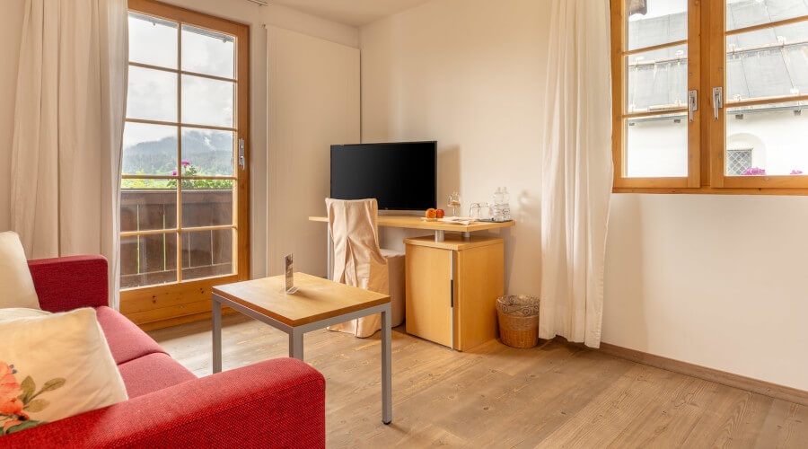 Hotelzimmer mit Fernseher und rotem Sofa