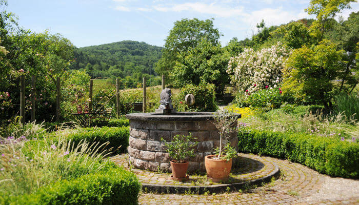 Steinbrunnen in einem Garten bei Sonnenschein