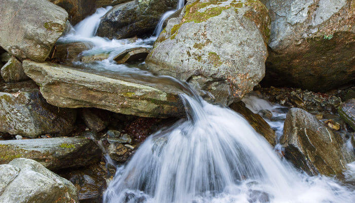 Wasser das über Steine fällt in einem Bergbach