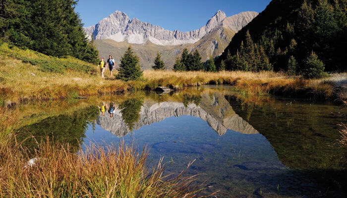 Wanderer vor See in der Moorlandschaft Alp Flix