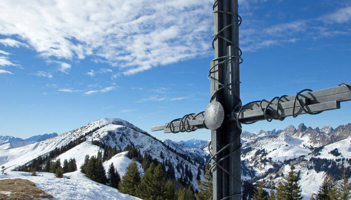 Kreuz auf einem Berg in der Sonne und Schnee